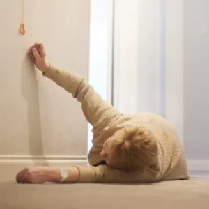 An elderly woman on the ground who has fallen and she is reaching out for help